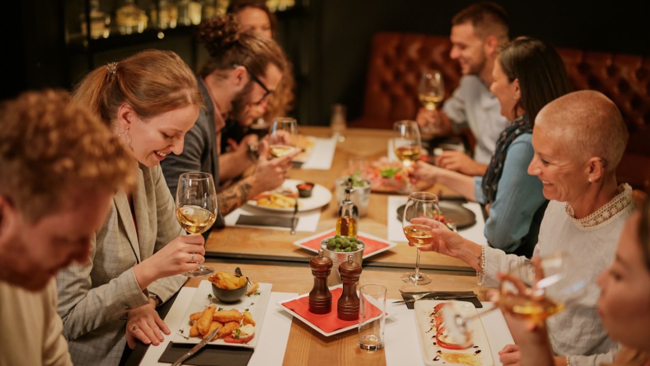 Eating Out a group of people setting at restaurant, for the article Mastering English Phrases for Restaurant Adventures.
