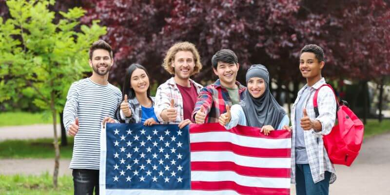 Master American Accent Group of non-native English speakers standing behind the USA flag, showcasing their journey to master the American accent from zero to fluency.