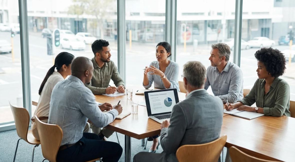 American business team discussing project updates after follow-up email in modern office meeting room.