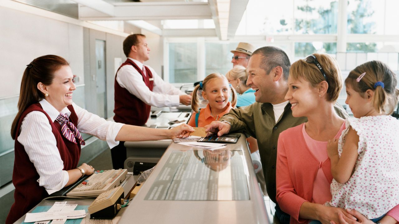 Traveler speaking to airport staff at check-in desk, using common English phrases to check in and inquire about baggage.