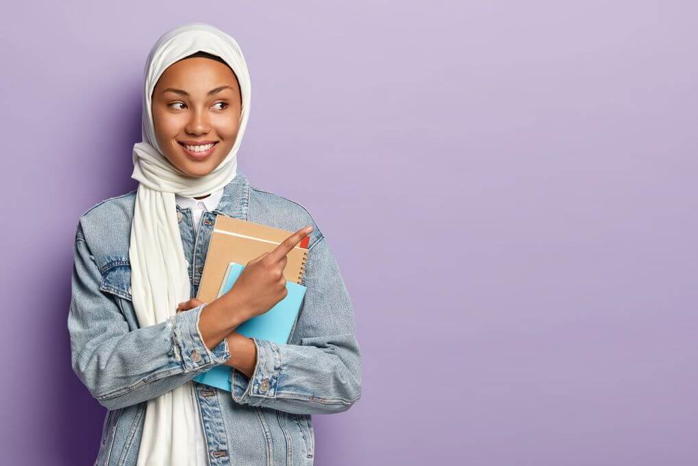 isolated-shot-satisfied-muslim-student-shows-awesome-advert-points-upper-right-corner-wears-white-veil-jean-jacket (1) Arabic Speakers English Mispronunciations